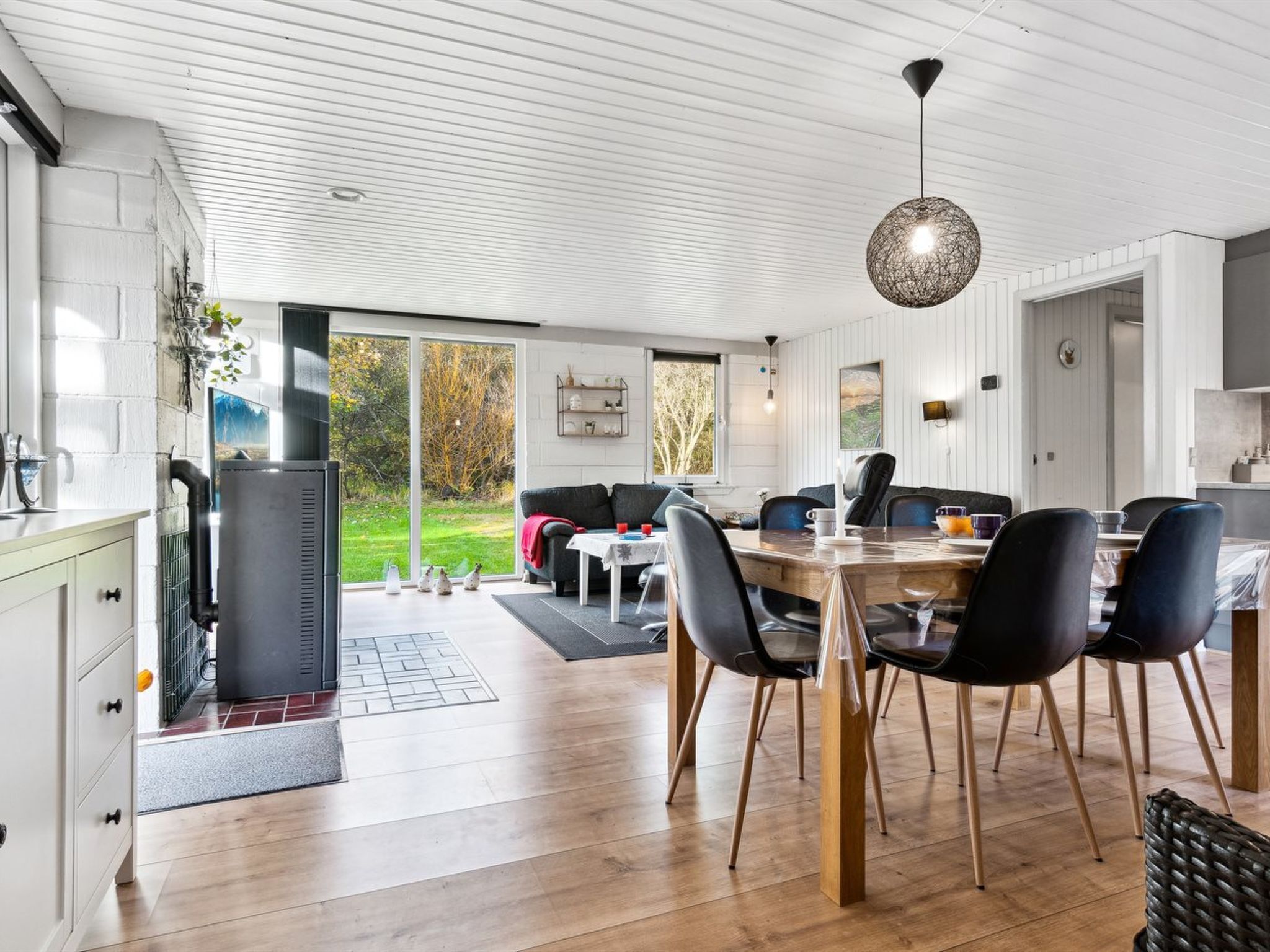 Een moderne keuken met een groot kookeiland, een eethoek met een ronde tafel en stoelen, en uitzicht op de omgeving.