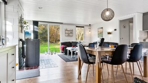 A modern kitchen with a large island, a dining area with a round table and chairs, and a view of the outdoors.