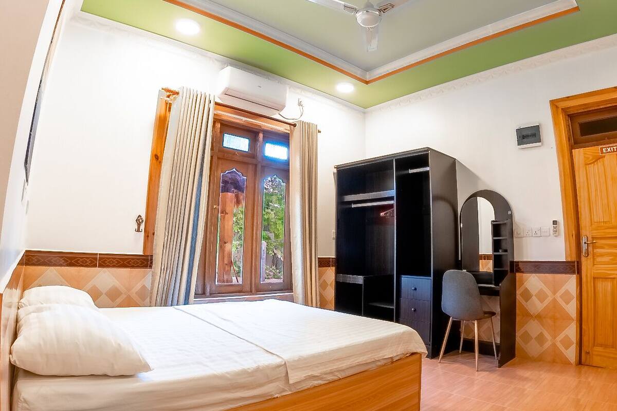 Un dormitorio con cama, escritorio, silla, armario y una puerta señalizada con