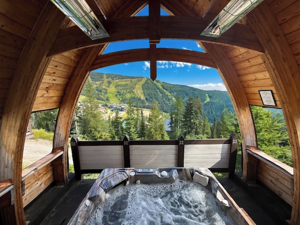 A wooden cabin with a hot tub and a scenic mountain view.