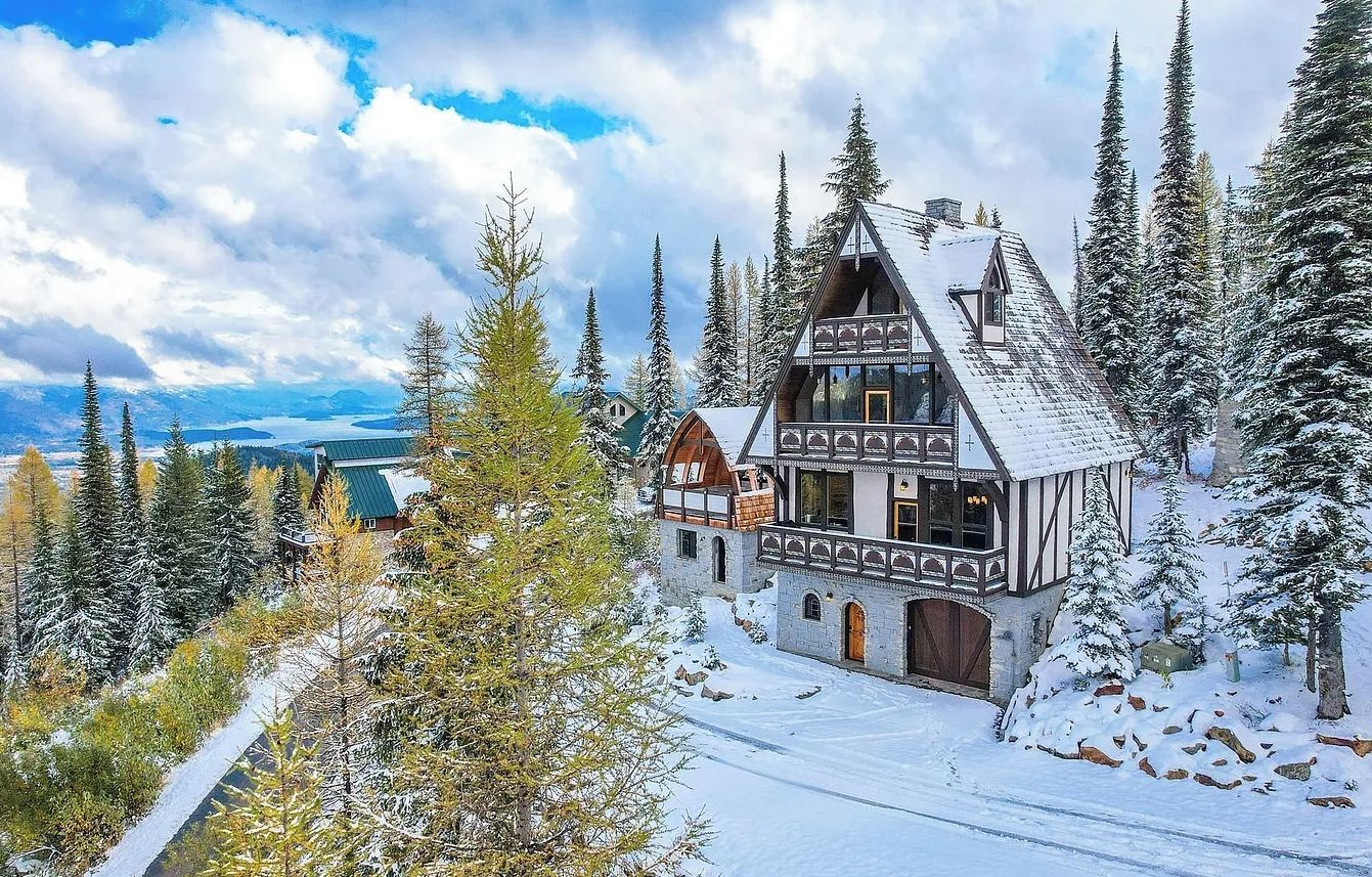 A traditional chalet-style building surrounded by snow-covered trees and a clear sky.