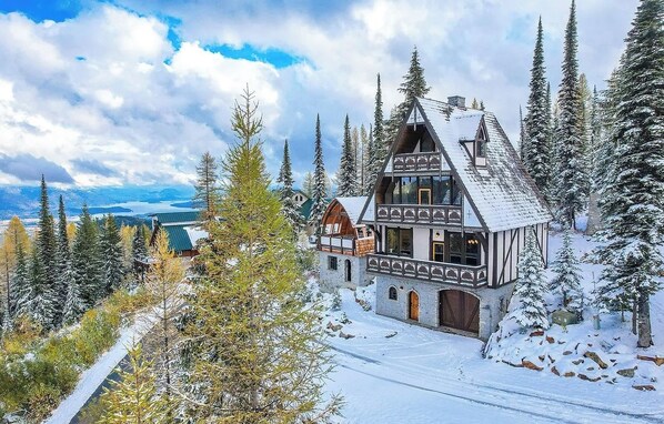 Un edificio de estilo chalete tradicional rodeado de árboles cubiertos de nieve y un cielo despejado.