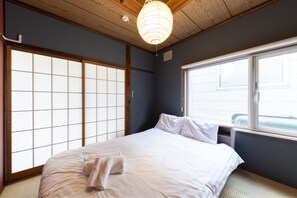Una stanza con un letto, porte scorrevoli shoji, una finestra e una lampada a sospensione.