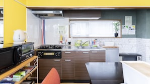 Une cuisine compacte dotée d’appareils électroménagers modernes, une fenêtre avec stores et un petit coin repas.