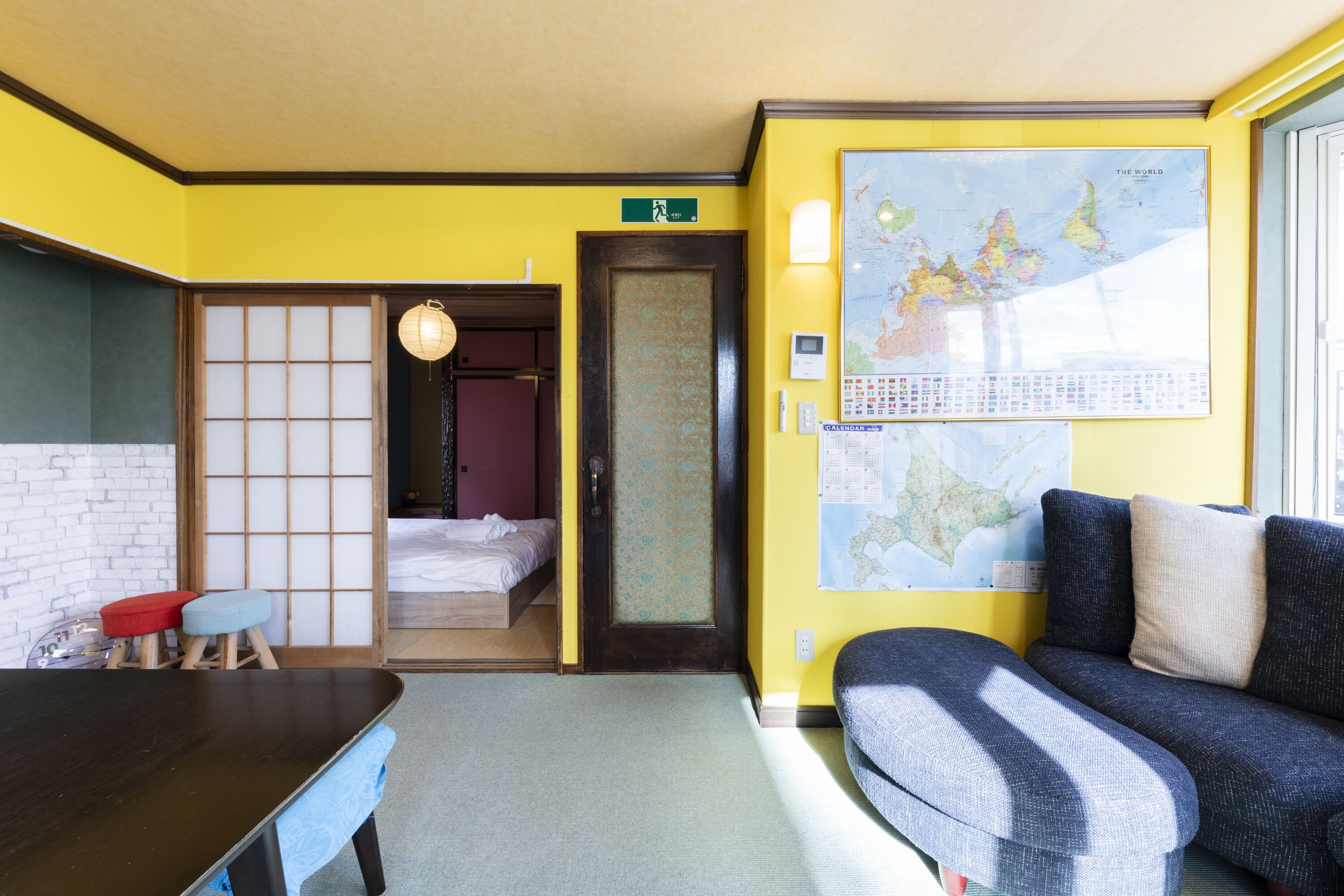 A room with a bed, a sofa, a table, and a map on the wall.