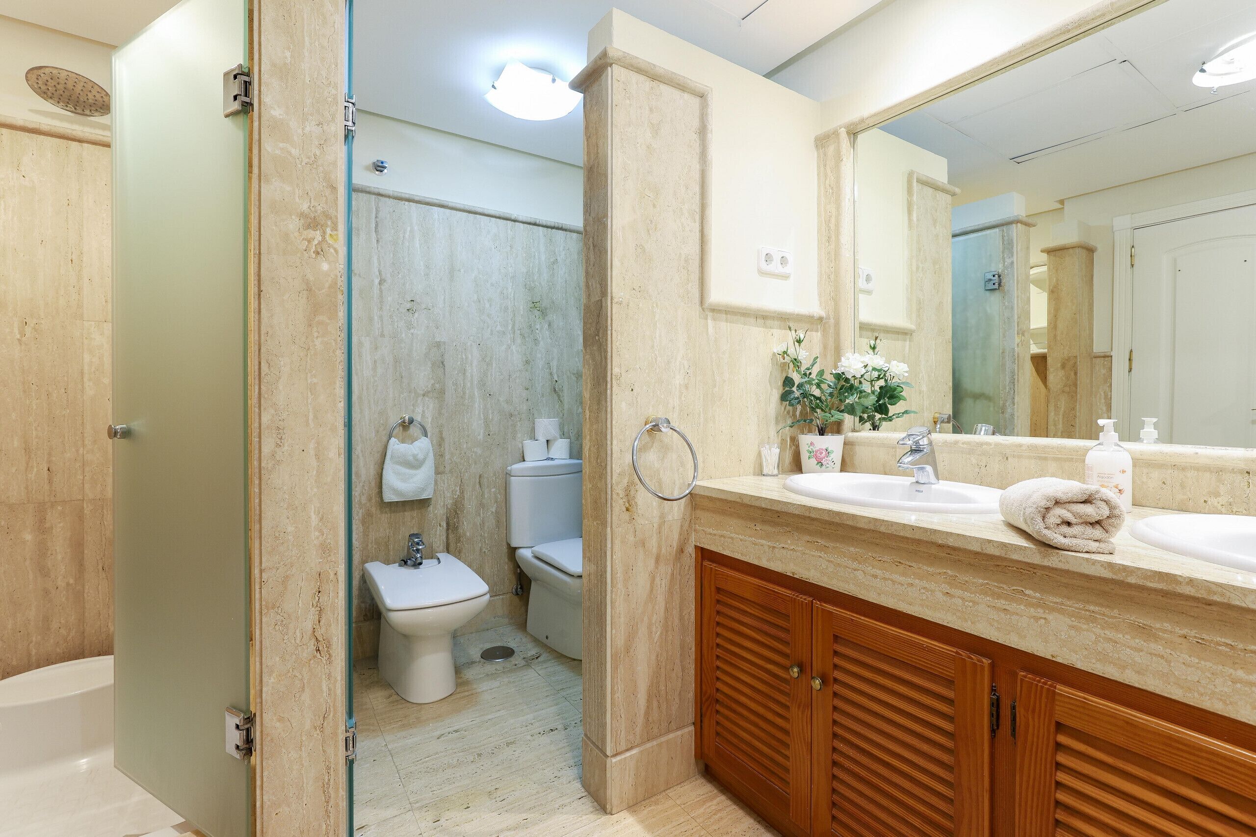 A bathroom with a shower, toilet, sink, and mirror.
