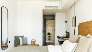 A modern bedroom with a bed, bedside table, and a desk with a laptop. - Beach Villas in Crete Alope & Ava (Ierapetra)