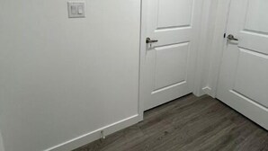 A hallway with white walls and wooden flooring. - Serene Haven in Harbour Landing (Regina)