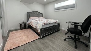 A bedroom with a bed, a desk, and a chair. - Serene Haven in Harbour Landing (Regina)