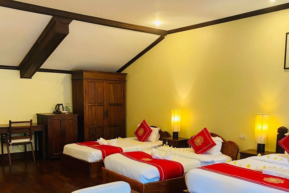 Une chambre d’hôtel avec deux lits, un bureau, une chaise et une petite table sur laquelle est posée une plante.