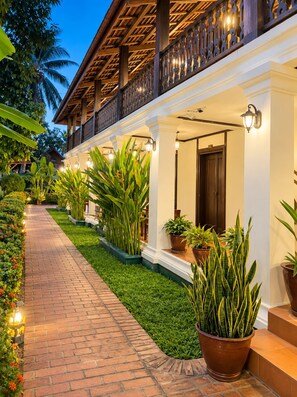 A hotel with a covered walkway, potted plants, and a well-lit entrance. - Luang Prabang Residence & Travel  (Luang Prabang)
