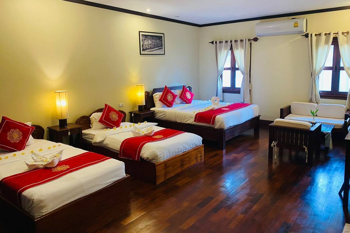 Une chambre d’hôtel avec deux lits, un bureau et une chaise. Il y a un tableau au mur et un appareil de climatisation fixé au mur.