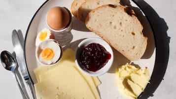 Un plato de desayuno con pan, huevos, queso, mantequilla y mermelada.