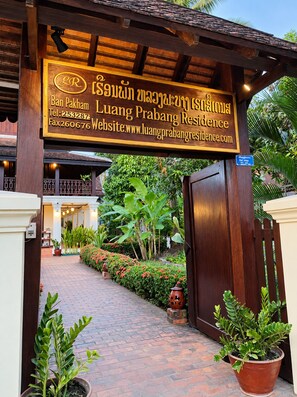Een houten bord met contactgegevens voor Luang Prabang Residence.