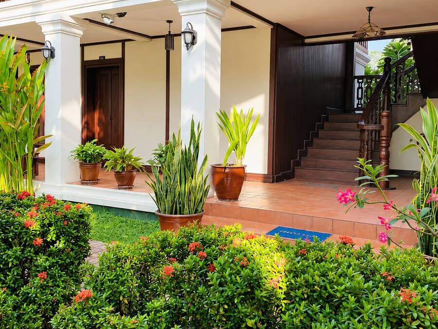 A hotel entrance with a covered porch, potted plants, and a staircase leading to the interior.