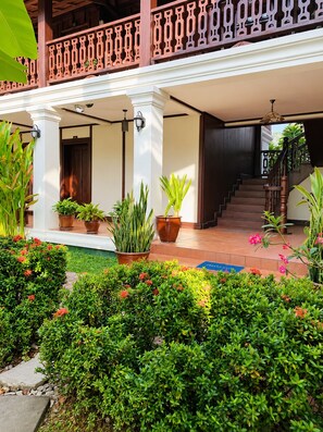 A hotel entrance with a covered porch, potted plants, and a staircase leading to the interior.