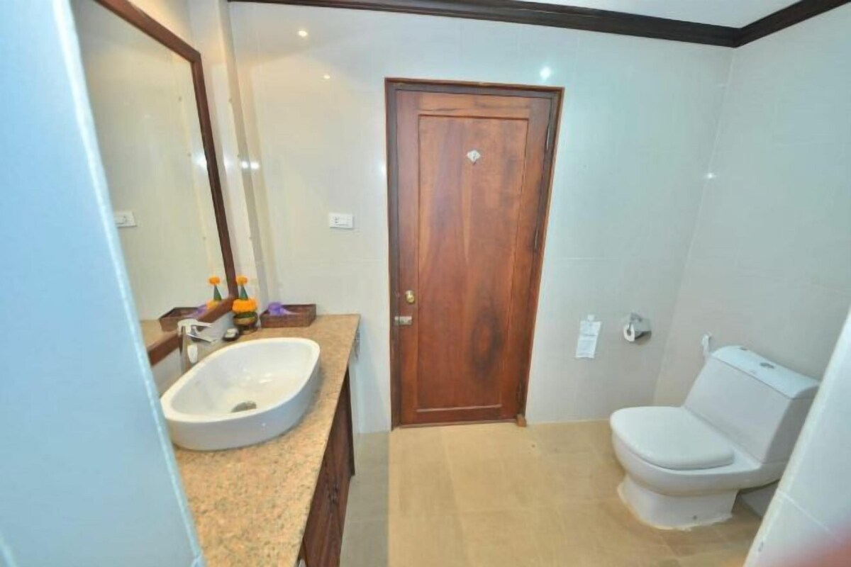 Un baño con puerta de madera, un lavamanos blanco y un inodoro.