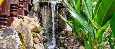 A waterfall cascading over rocks in a garden setting.