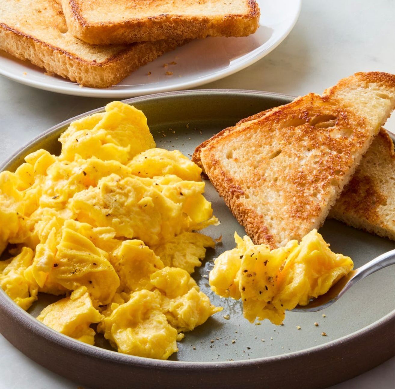 Scrambled eggs and toasted bread on a plate.