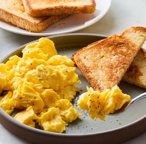 Scrambled eggs and toasted bread on a plate.
