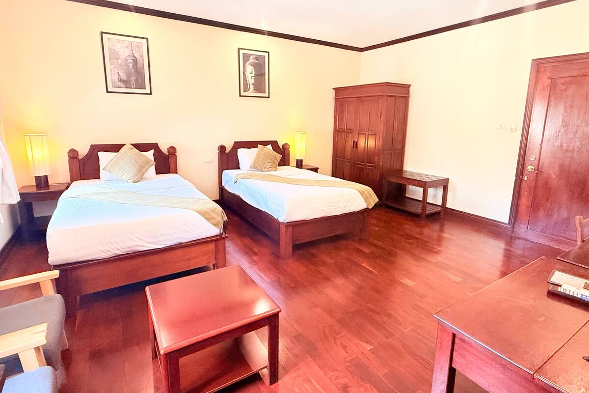 Une chambre d’hôtel avec deux lits, une armoire, un bureau et une chaise.