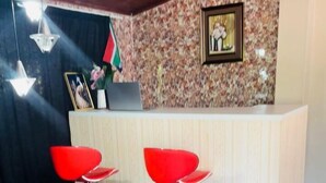A reception area with a wooden ceiling, a patterned wall, and two red bar stools. - Comrades Oasis Guest House  (Pietermaritzburg)