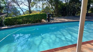 A clear swimming pool with a stone deck and a wooden fence. - Comrades Oasis Guest House  (Pietermaritzburg)