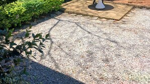 A garden with a central table and benches, surrounded by gravel and greenery. - Comrades Oasis Guest House  (Pietermaritzburg)