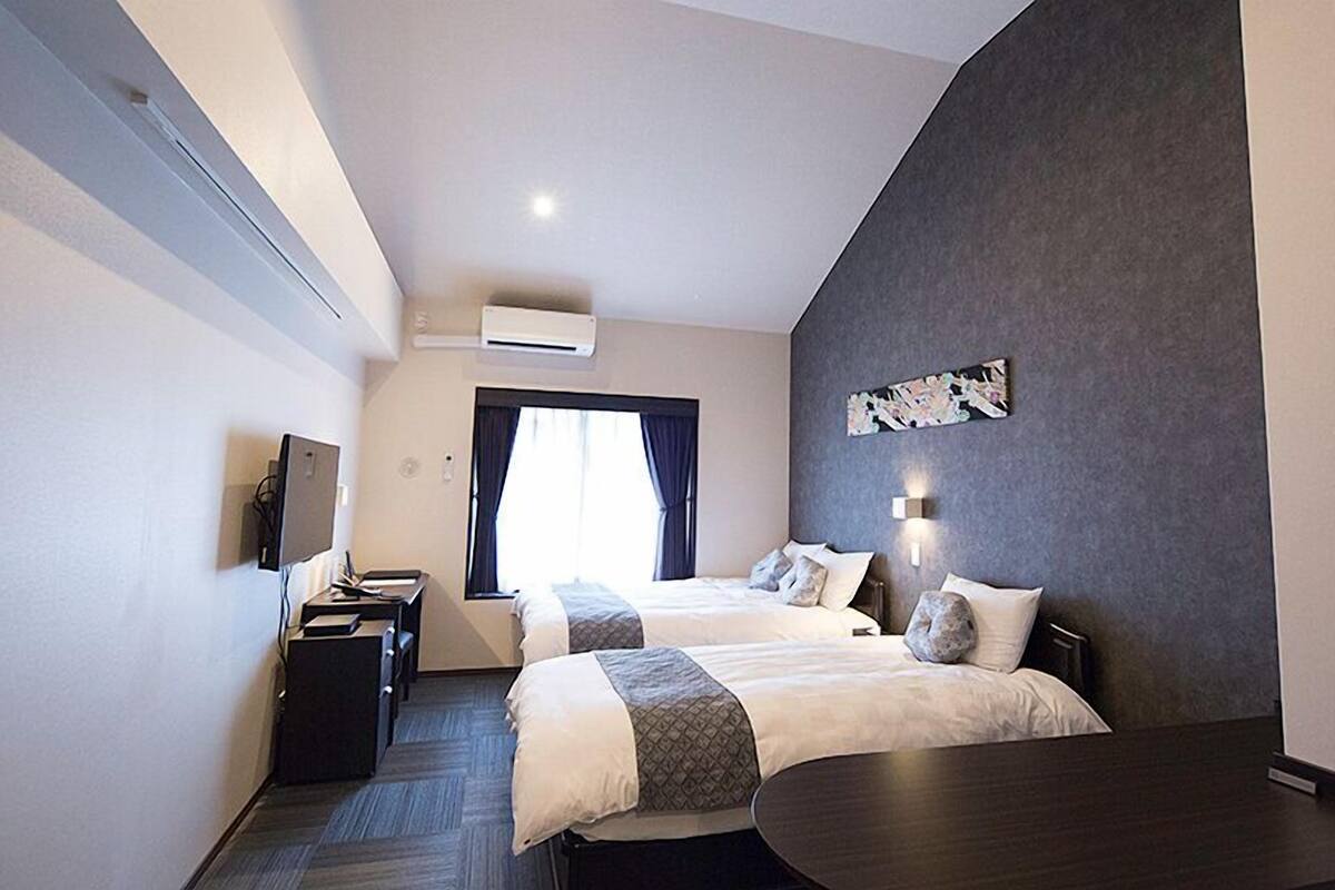 Une chambre d’hôtel moderne équipée de deux lits, d’un bureau et d’une chaise.