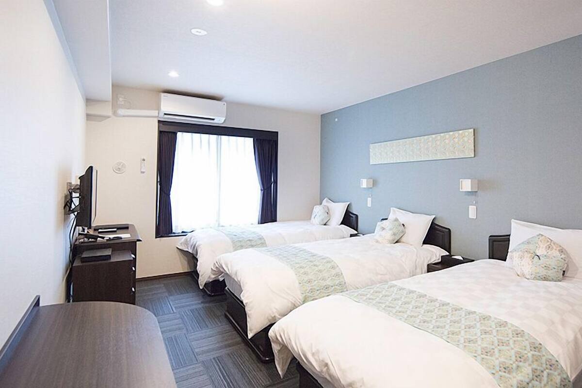 Une chambre d’hôtel avec deux lits, un bureau, une télévision et un appareil de climatisation.