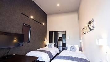 Une chambre d’hôtel avec deux lits, un bureau, un téléviseur à écran plat et une petite kitchenette.