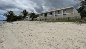 Ein Strandgrundstück mit einem modernen Haus, das ein Flachdach und große Fenster hat.