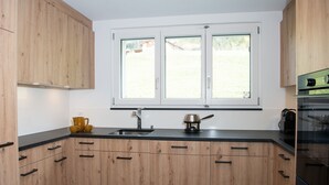 Une cuisine moderne avec des meubles en bois, un plan de travail noir, un évier et une fenêtre donnant sur l’extérieur.