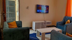 A living room with two armchairs, a coffee table, and a TV mounted on the wall.
