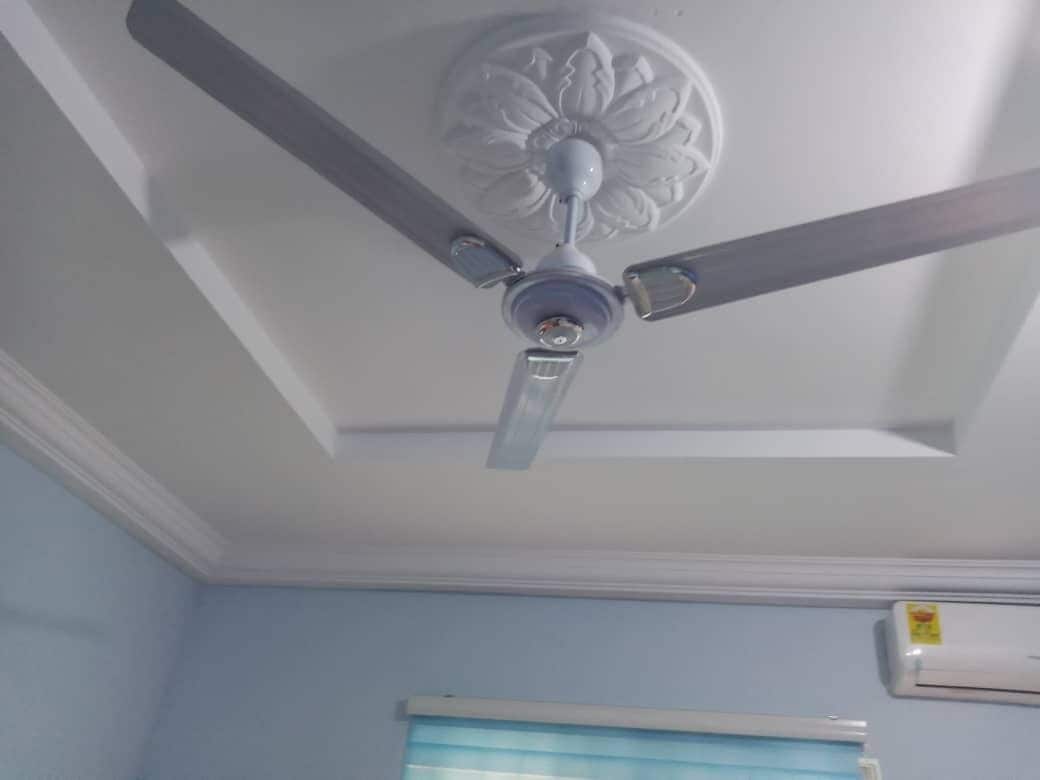 A ceiling fan with three blades and a decorative central part.
