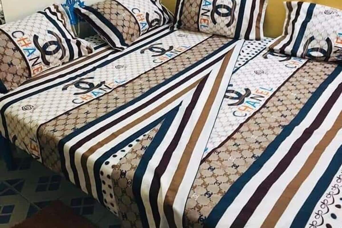 Ein Bett mit einer gestreiften Bettdecke und Kissen mit dem Chanel-Logo.