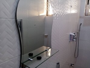Bathroom features a curved glass shower enclosure with a handheld showerhead and wall-mounted faucet.