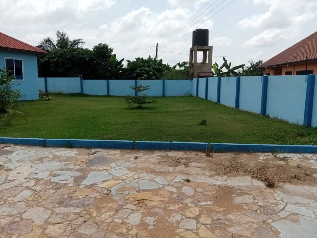 Un cortile con pavimento in pietra, recinzione blu e un serbatoio d'acqua sullo sfondo.