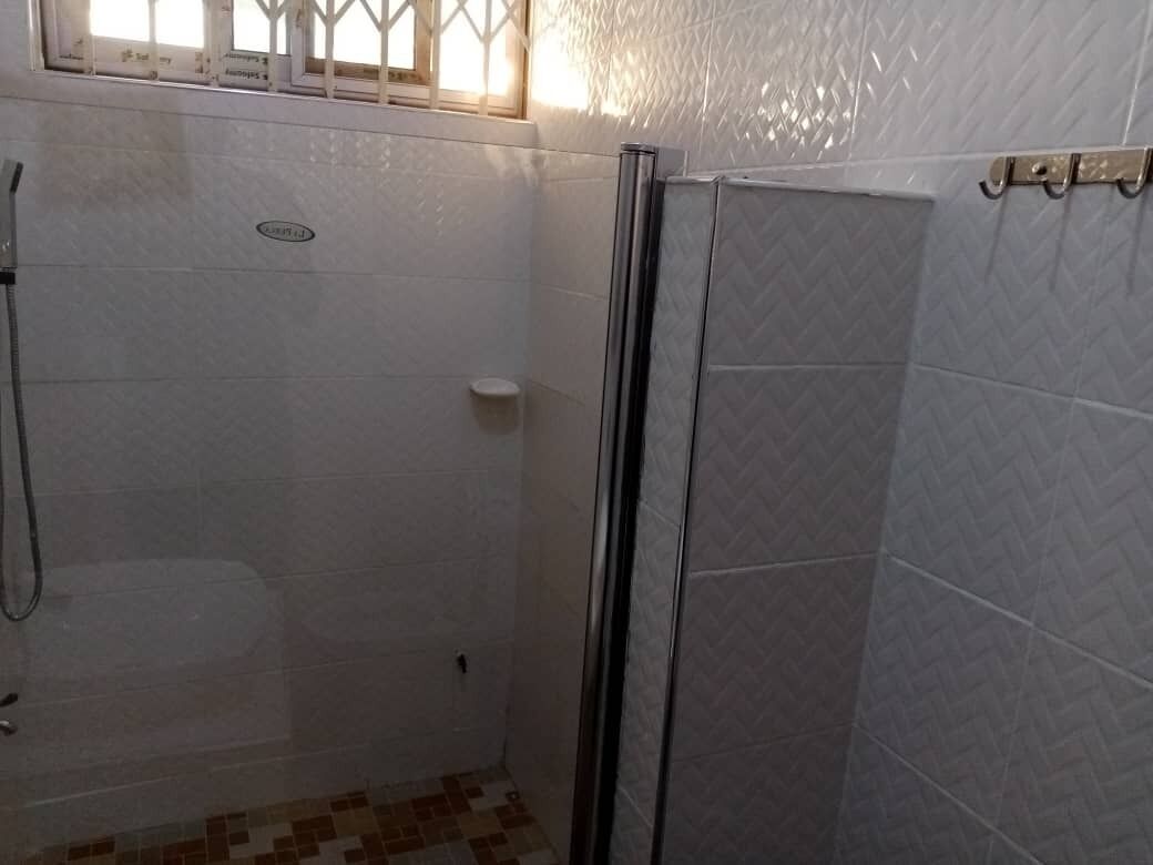Casa de banho com zona de duche, sanita e lavatório.