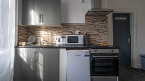 A compact kitchen with a microwave, toaster, and a small refrigerator. - Lovely 2-bed Studio10 in Coventry (Coventry)
