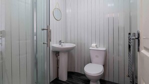 A small, modern bathroom with a glass shower enclosure, a white sink, and a toilet. - Lovely 2-bed Studio10 in Coventry (Coventry)