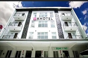 A hotel with a modern facade, balconies, and a sign for 'SOAK N GO' at the entrance. - Khotel near T3 Airport (Pasay)