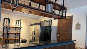 A modern kitchen with a built-in refrigerator, a wooden countertop, and a glass shelf with wine glasses. - Khotel near T3 Airport (Pasay)