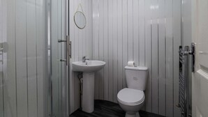 A small, modern bathroom with a white sink, toilet, and a glass shower enclosure. - Impeccable Flat 1-bed Studio12 in Coventry (Coventry)