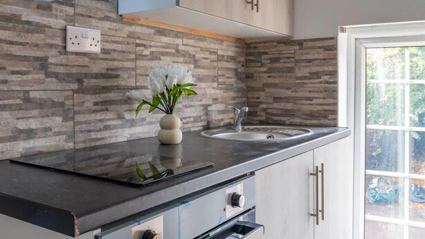 Een moderne keuken met een betegelde achterwand, een inbouwspoelbak en een raam met uitzicht op groen.