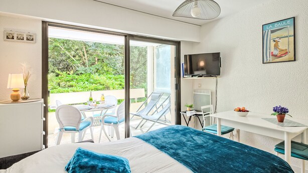 Une chambre d’hôtel moderne équipée d’un lit, d’un bureau, d’une télévision et d’un balcon avec coin salon extérieur.