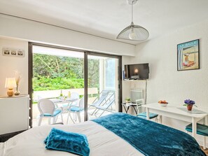 Ett modernt hotellrum med en säng, ett skrivbord, en TV och en balkong med utemöbler.