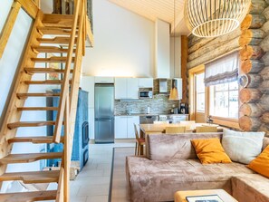 Ein gemütliches Wohnzimmer mit einer Holztreppe, einem Sofa mit orangen Kissen und einem Kamin.