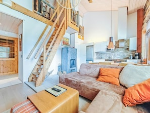 Un interior moderno con una escalera de madera, un sofá, una mesa de centro y una zona de cocina.