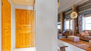 En dörr av trä, en hall, ett vardagsrum med en soffa, ett soffbord och en hängande lampa.